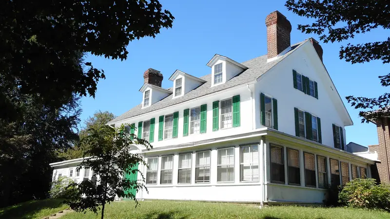White historic house with green shutters and a porch