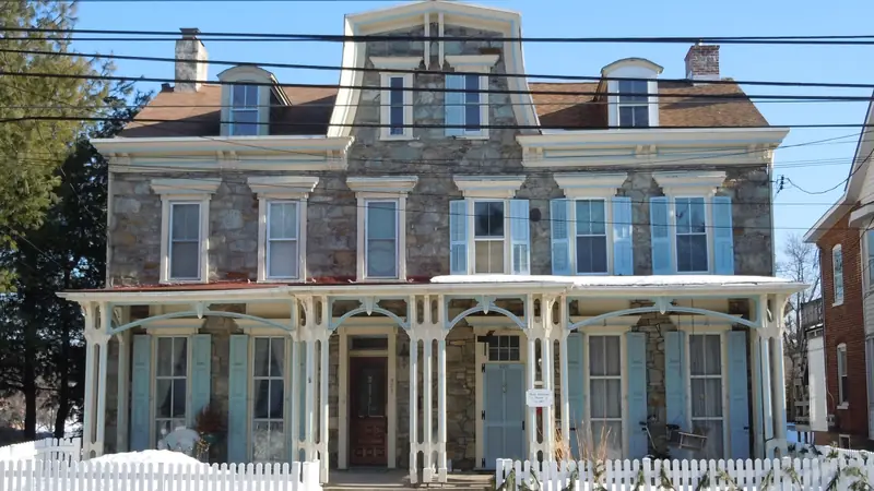 Historic stone twin house with a two-story porch